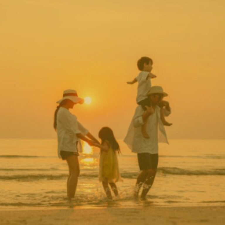 Família feliz apreciando o pôr do sol do mar na praia.