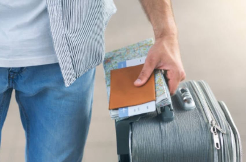 Homem que vai ao vôo com mala de viagem, passaporte e bilhete de avião.