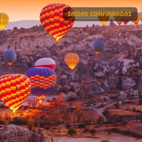 Momento único do nascer do sol na Capadócia, Turquia, com dezenas de balões de ar quente sobrevoando as formações rochosas.